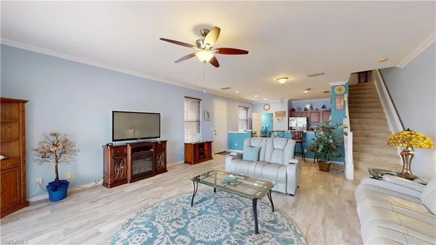 Living room featuring crown molding, light wood-type flooring, and ceiling fan