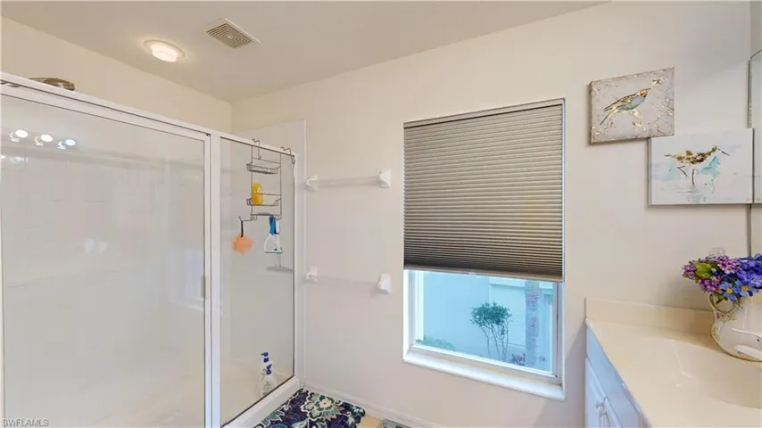 Bathroom featuring a shower with shower door and vanity