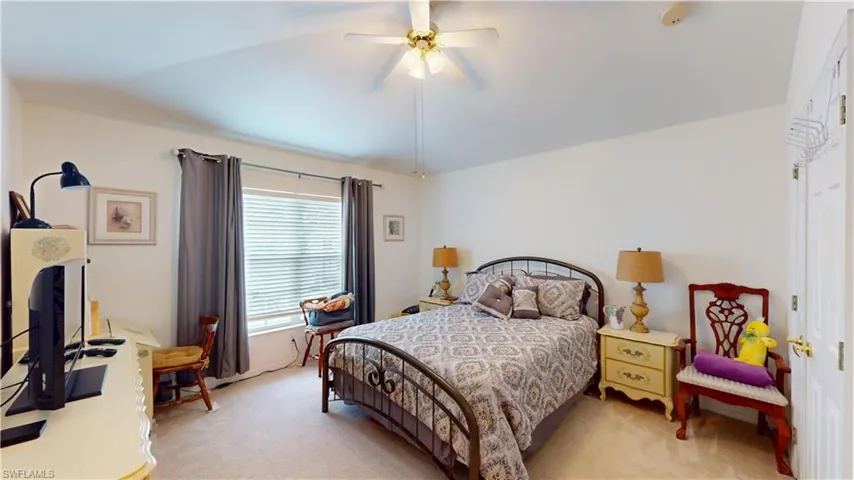 Carpeted bedroom featuring vaulted ceiling and ceiling fan