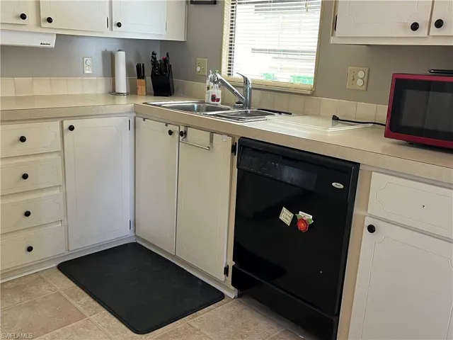 Kitchen with sink, black dishwasher, and white cabinets