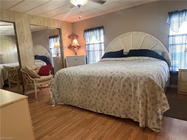 Bedroom featuring wooden walls, multiple windows, and ceiling fan
