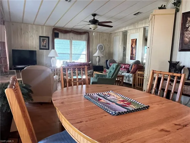 Dining space with wood walls, ceiling fan, and vaulted ceiling