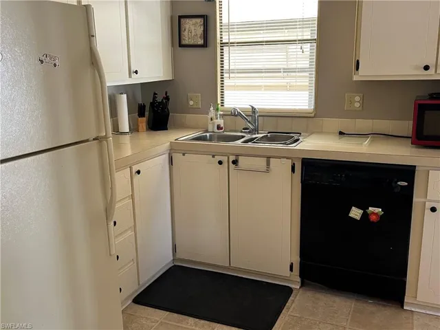 Kitchen featuring dishwasher, white cabinetry, sink, and refrigerator