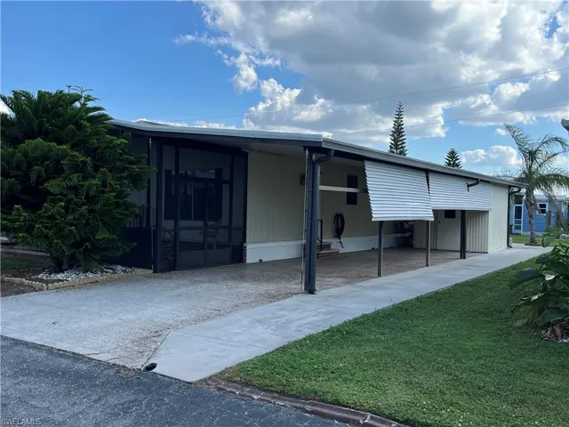 Manufactured / mobile home with a front yard, a sunroom, and a carport