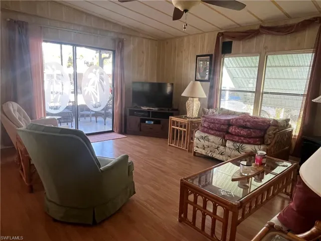 Living room featuring wood walls, lofted ceiling, hardwood / wood-style floors, and ceiling fan