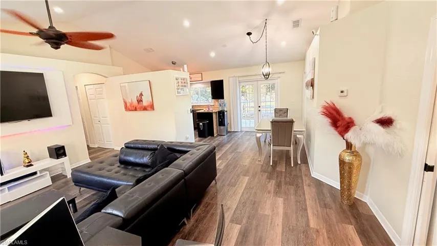 Living area with wood finished floors, arched walkways, a ceiling fan, french doors, and lofted ceiling