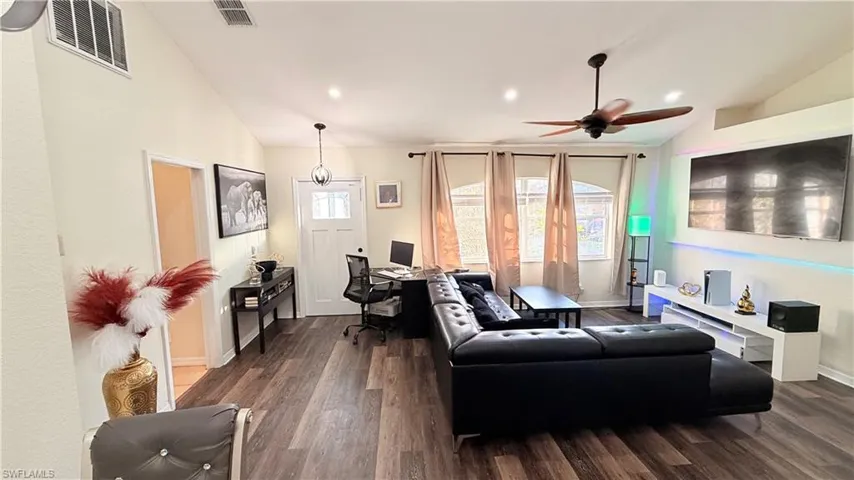 Living room with vaulted ceiling, an office area, dark wood-style floors, ceiling fan, and recessed lighting