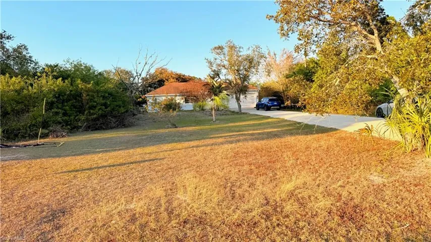 View of grassy yard with driveway and a carport