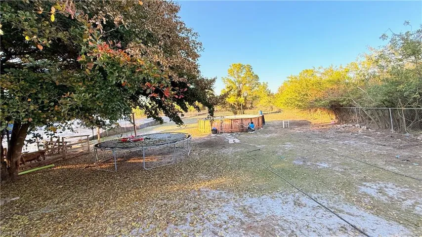 Fenced yard with a trampoline and a patio area