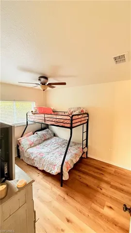 Bedroom featuring light wood-type flooring, a ceiling fan, and a textured ceiling