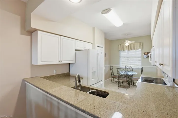 Kitchen with white appliances, white cabinetry, and ceiling fan