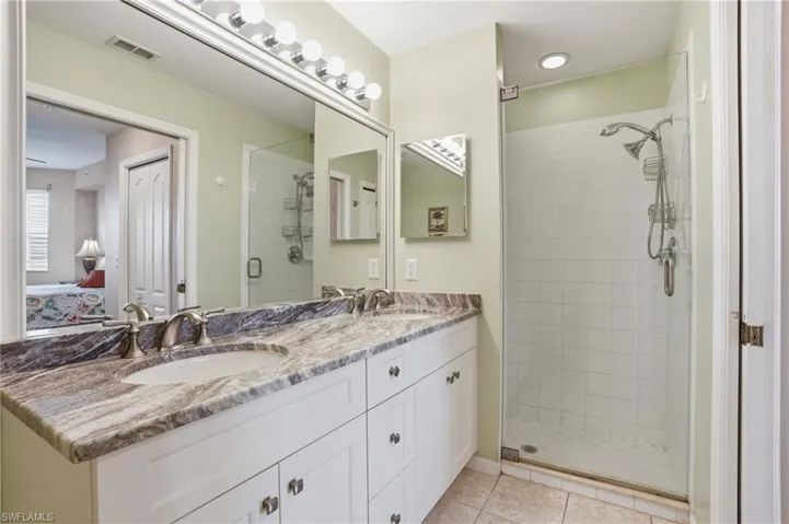 Bathroom featuring double vanity, ensuite bath, a shower stall, and light tile patterned floors