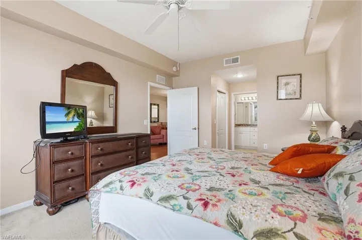 Bedroom with light colored carpet, ceiling fan, ensuite bath, and a closet