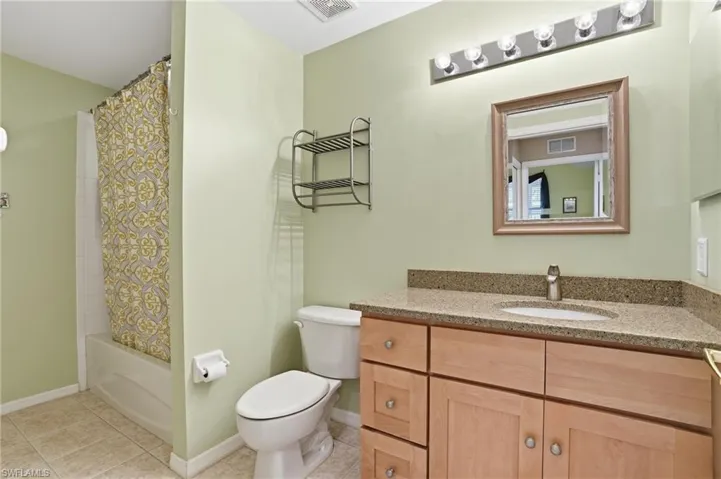 Full bathroom featuring vanity, shower / bath combination with curtain, and light tile patterned floors