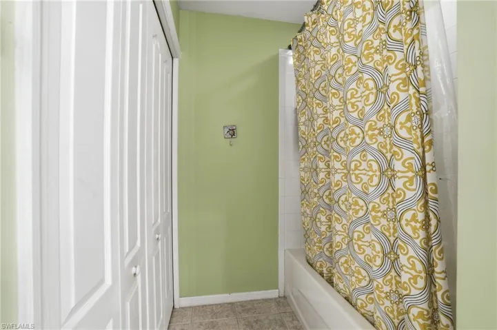 Bathroom featuring shower / tub combo with curtain and light tile patterned floors