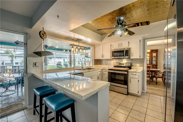 Kitchen featuring white cabinetry, appliances with stainless steel finishes, a breakfast bar area, tasteful backsplash, and a raised ceiling