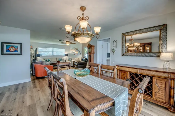 Dining space with ceiling fan with notable chandelier and light hardwood / wood-style flooring