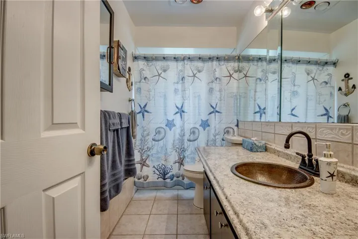 Bathroom featuring backsplash, tile flooring, oversized vanity, and toilet