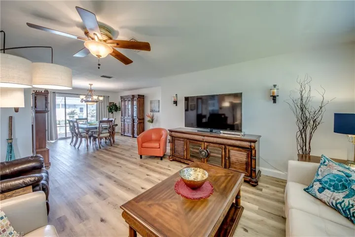 Living room featuring ceiling fan with notable chandelier and light hardwood / wood-style flooring