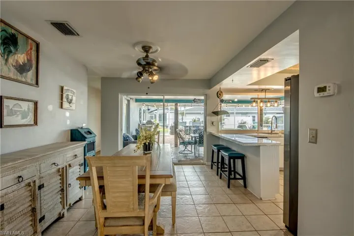 Dining space featuring ceiling fan with notable chandelier, sink, and light tile floors