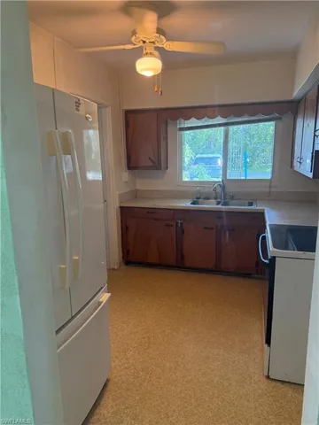 Kitchen featuring sink, white appliances, and ceiling fan