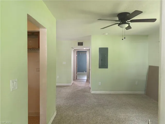 living room with light carpet, electric panel, and ceiling fan