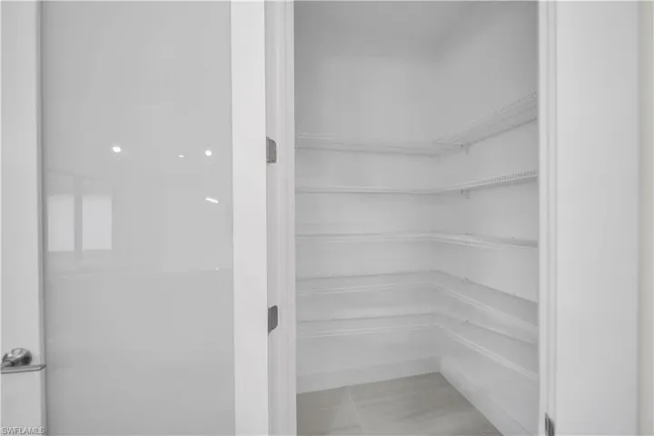 Spacious pantry with multiple wire shelving units and light-toned floor tiling
