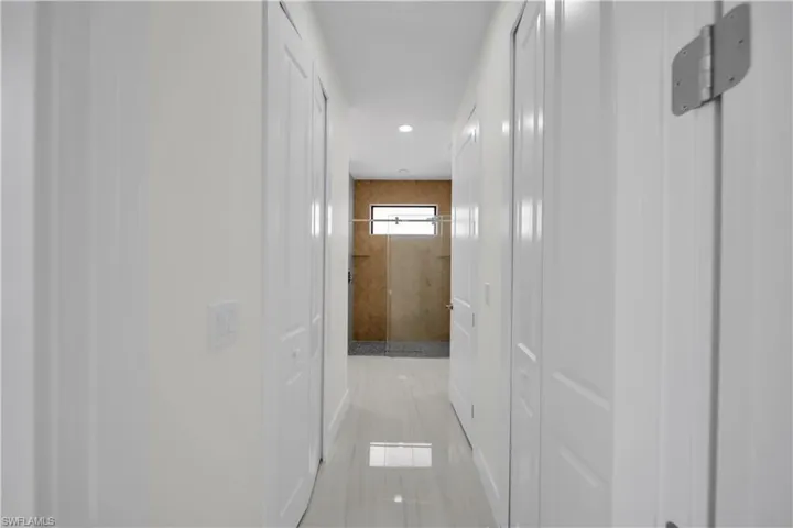 Hallway with white paneled doors, recessed lighting, and tile flooring