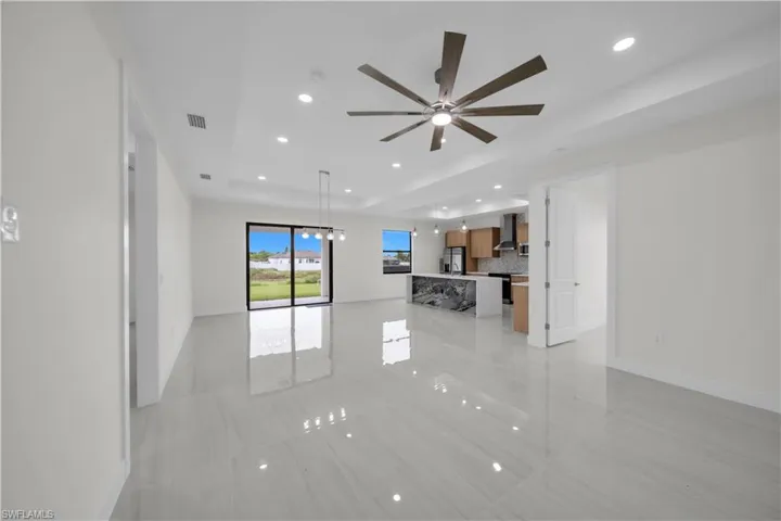 Open-concept living space featuring high ceilings, recessed lighting, polished tile flooring, and a modern ceiling fan
