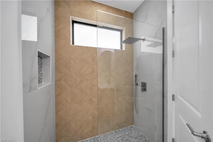 Walk-in shower with clear glass enclosure and rainfall showerhead