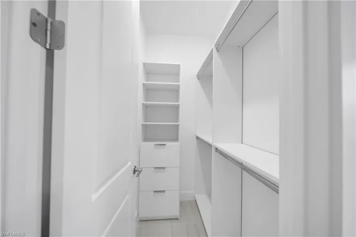 Custom closet system with white shelving, integrated drawers, and hanging rods