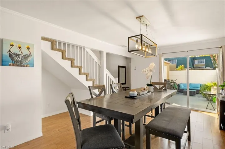 Dining room with crown molding, wood finished floors, stairs, and a chandelier