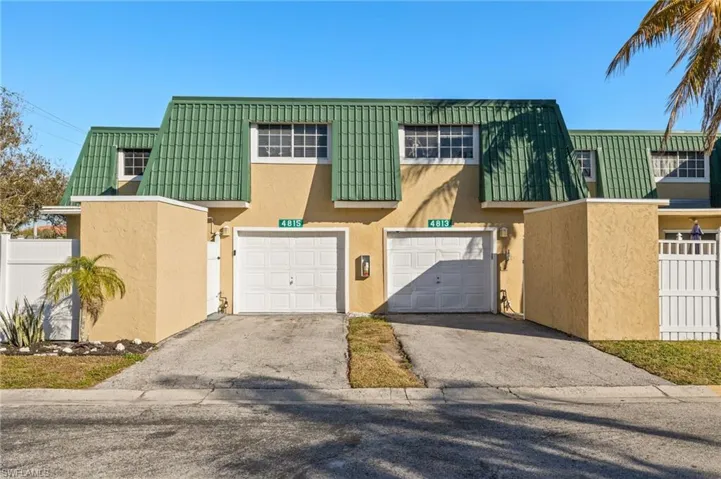 Townhome / multi-family property featuring stucco siding, driveway, and mansard roof