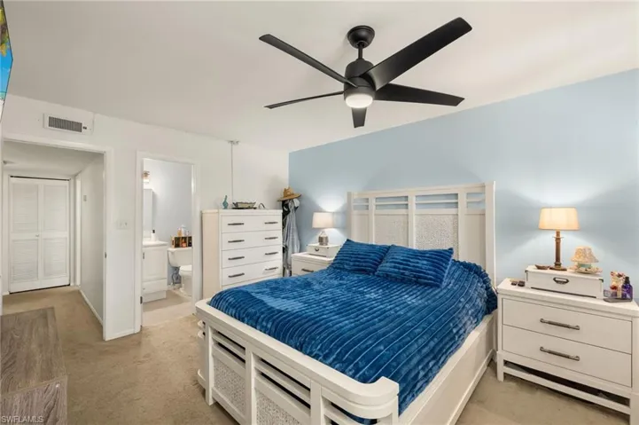 Bedroom with light carpet, ensuite bath, and ceiling fan