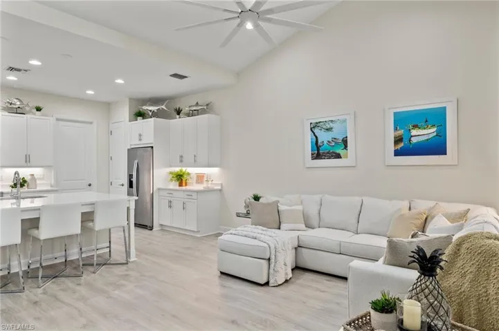 Living room with high vaulted ceiling, sink, light wood-type flooring, and ceiling fan