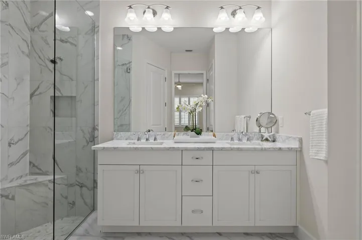 Bathroom featuring dual vanity, a shower with shower door, and tile patterned flooring