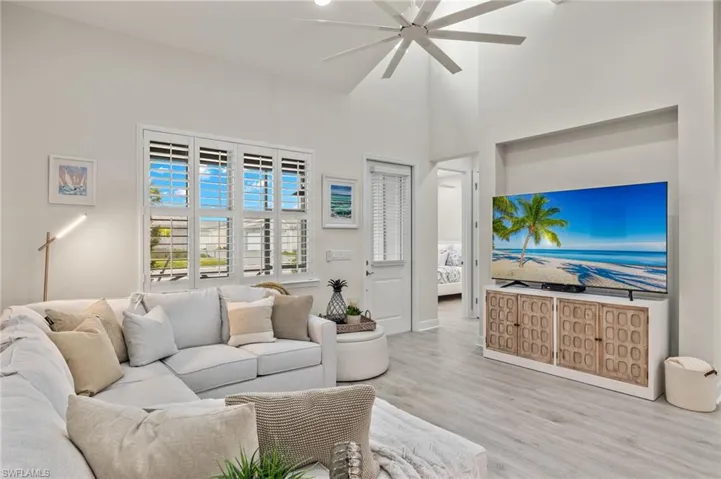 Living room with light hardwood / wood-style flooring, ceiling fan, and a high ceiling