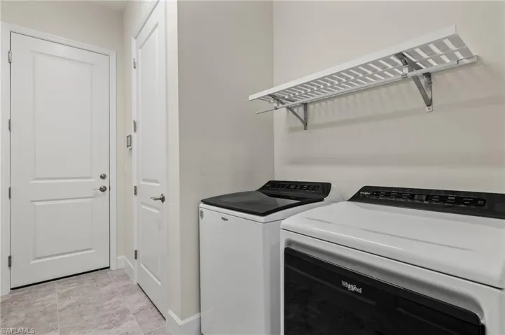 Clothes washing area featuring washing machine and dryer and light tile patterned floors