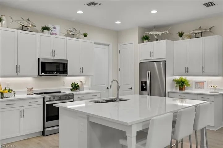 Kitchen featuring white cabinetry, an island with sink, light hardwood / wood-style floors, appliances with stainless steel finishes, and sink