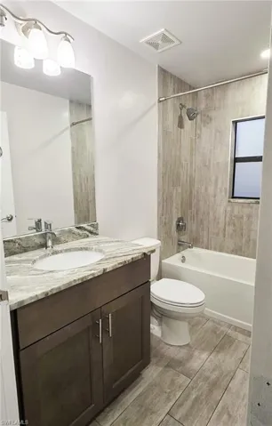 Bathroom featuring vanity, shower / tub combination, and wood tiled floors