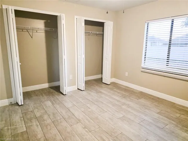 Unfurnished bedroom featuring multiple closets and light wood-style floors