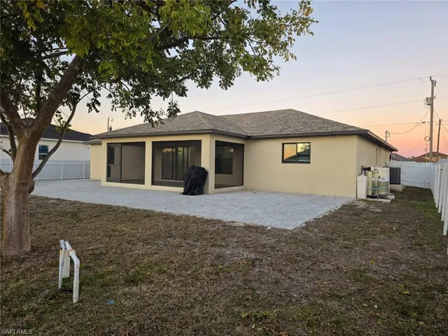 Back of property with stucco siding, a fenced backyard, a patio, a shingled roof, and a sunroom