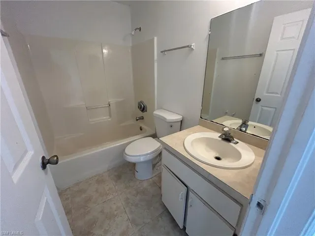 Bathroom with vanity, shower / washtub combination, and light tile patterned flooring