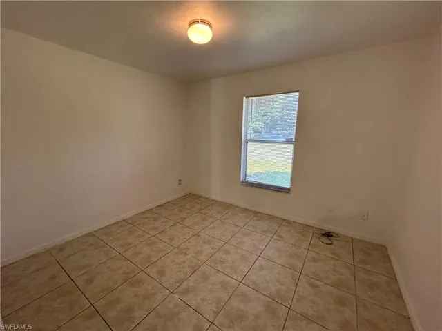 Empty room featuring light tile patterned floors and baseboards