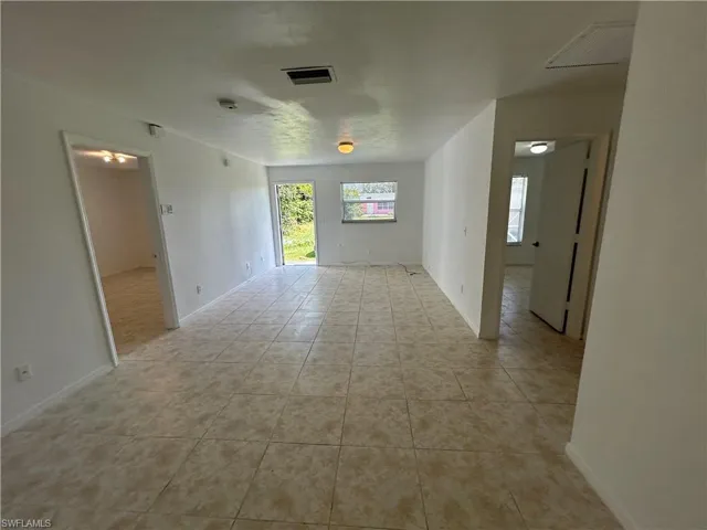 Empty room with light tile patterned flooring and baseboards