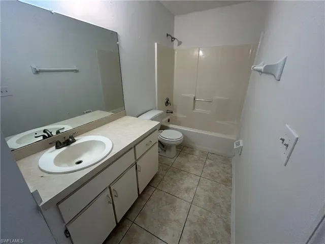 Full bath with vanity, light tile patterned floors, and shower / bath combination