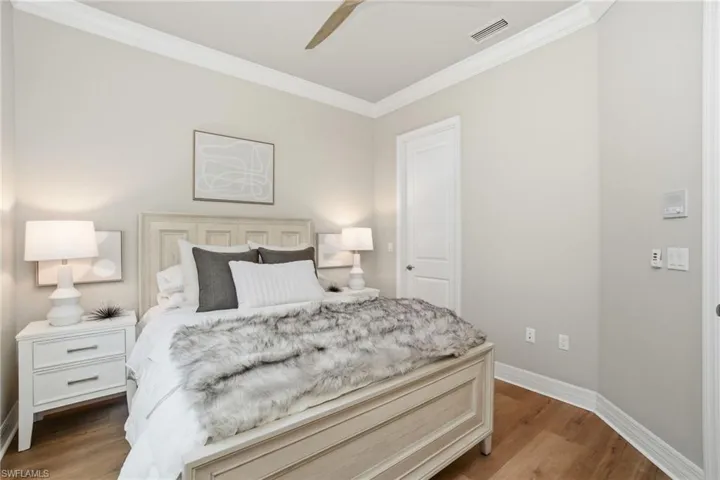 Thoughtfully designed bedroom with crown molding, wood-look floors, and soft neutral tones.