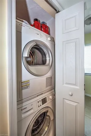 Laundry area with tile patterned floors and stacked washing maching and dryer
