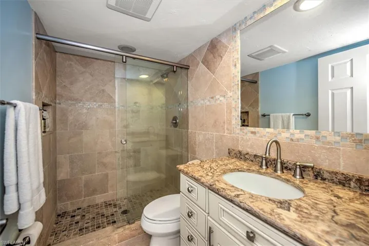 Bathroom featuring vanity, toilet, tile walls, tasteful backsplash, and an enclosed shower