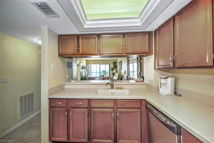 Kitchen featuring dishwasher, a raised ceiling, ornamental molding, and sink